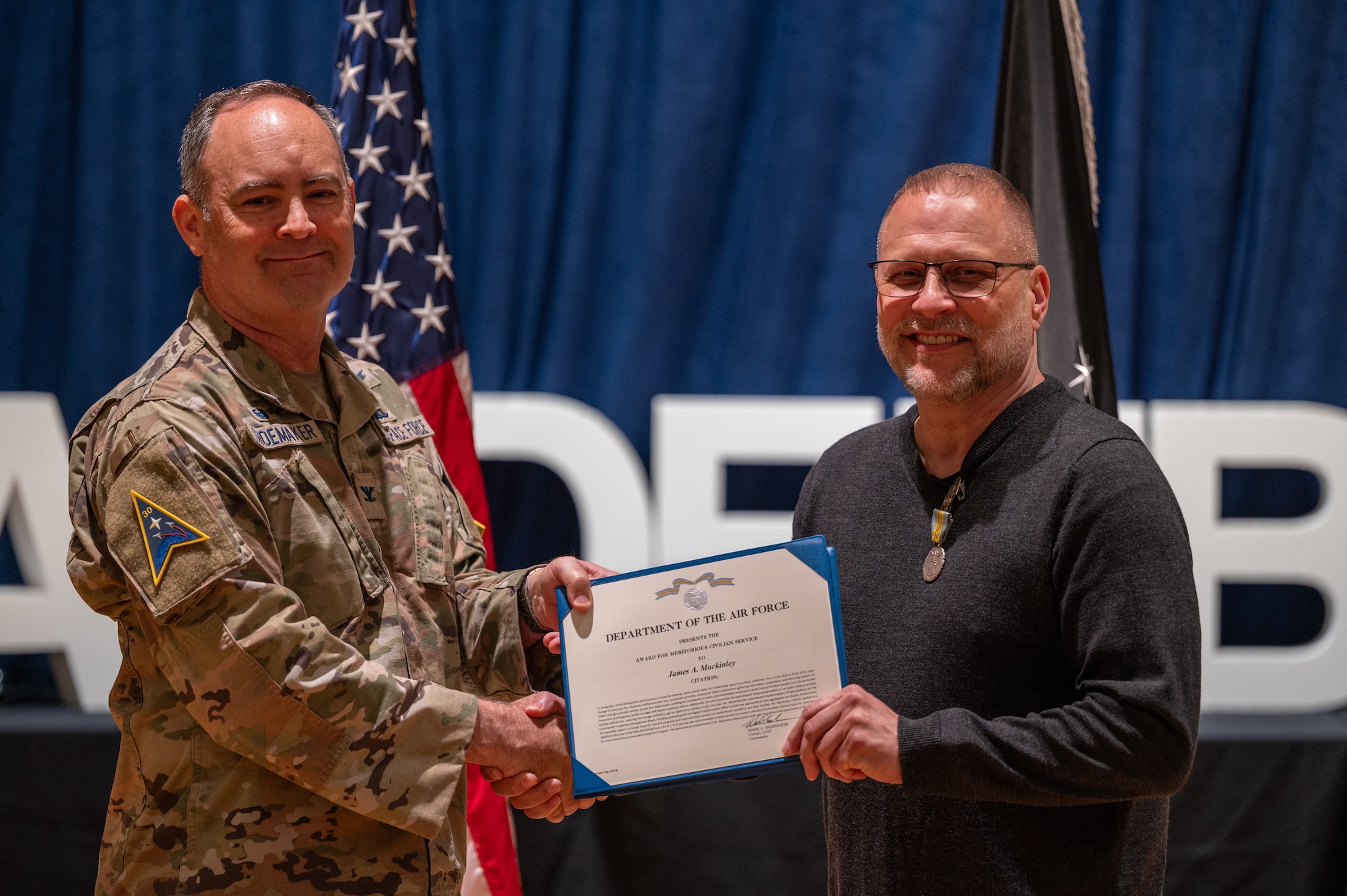 U.S. Space Force Col. Mark Shoemaker, Space Launch Delta 30 commander, left, presents the meritorious civilian service award to James Mackinley, Space Launch Delta 30 inspector general, during a commander’s call at Vandenberg Space Force Base, Calif., June 3, 2025. During the all-call, Shoemaker, along with other SLD 30 leadership, highlighted the achievements of the Guardians and Airmen on the installation over the course of Shoemaker’s command and the execution of the Delta’s strategic objectives.
