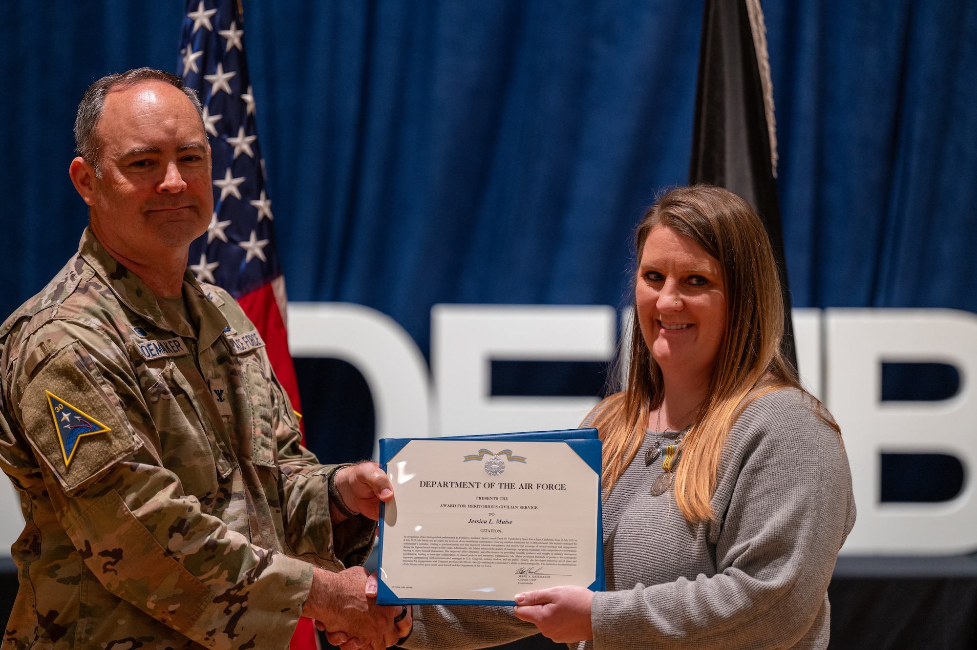 U.S. Space Force Col. Mark Shoemaker, Space Launch Delta 30 commander, left, presents the meritorious civilian service award to Jessica Muise, Space Launch Delta 30 commander’s secretary, during a commander’s call at Vandenberg Space Force Base, Calif., June 3, 2025. During the all-call, Shoemaker, along with other SLD 30 leadership, highlighted the achievements of the Guardians and Airmen on the installation over the course of Shoemaker’s command and the execution of the Delta’s strategic objectives.