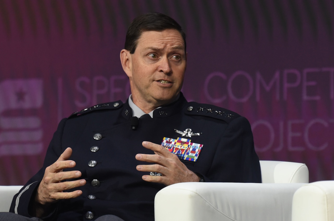 A man wearing a formal military uniform sits in a chair and speaks.