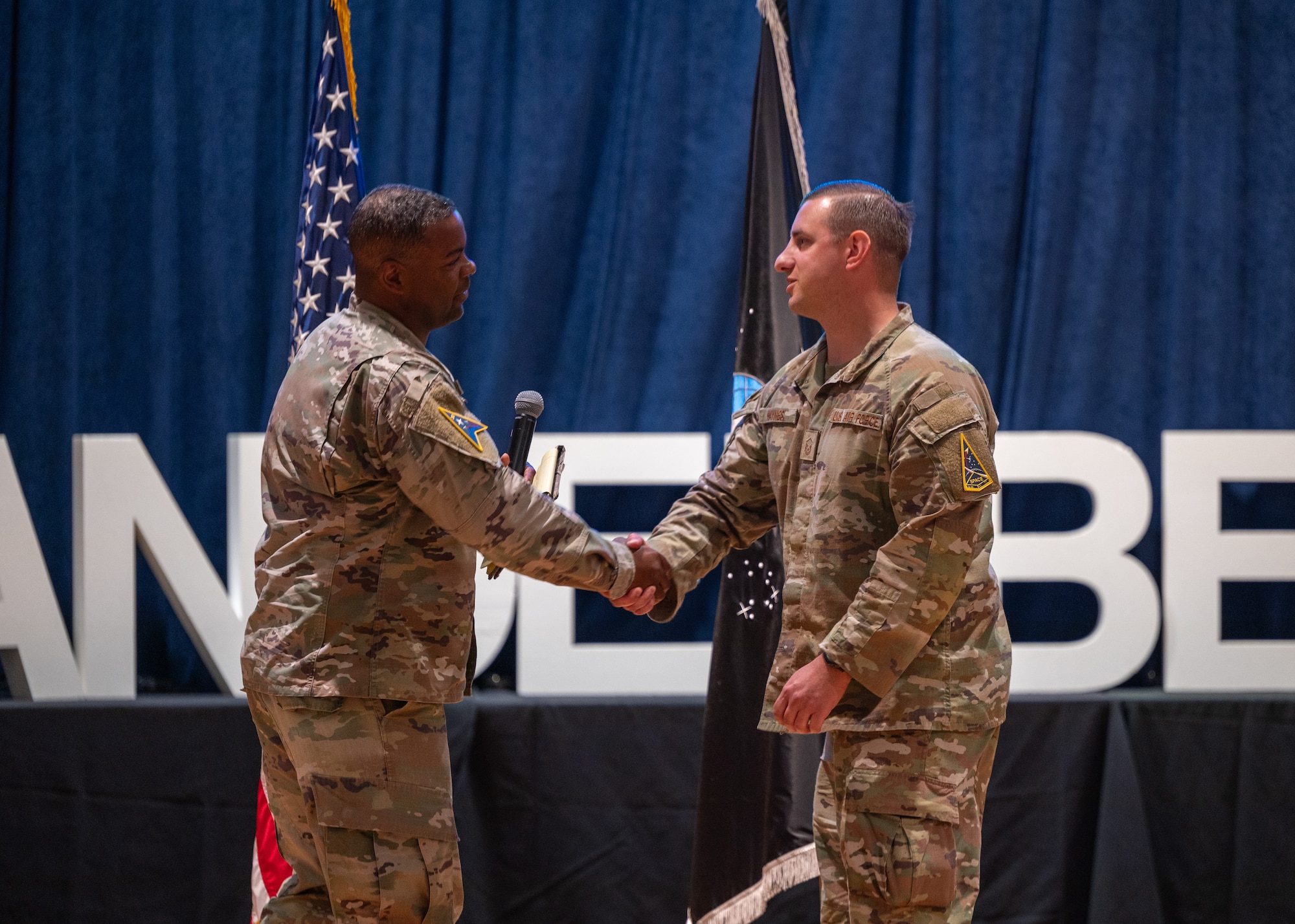 U.S. Space Force Chief Master Sgt. Jay Harris, left, presents a coin to U.S. Air Force Master Sgt. Andrew Haynes, 30th Operations Support Squadron senior enlisted leader, during an all-call at Vandenberg Space Force Base, Calif., June 3, 2025. Haynes stepped into the SEL role, normally held by a USSF Guardian, due to a manning shortage and was recognized for his efforts.