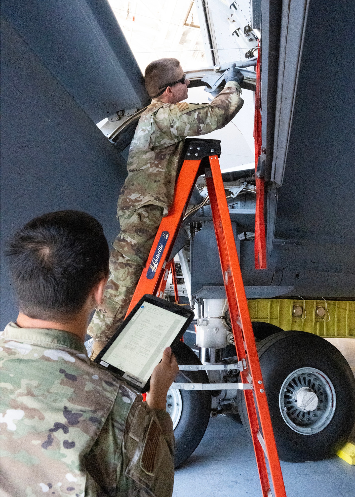 U.S. Air Force Tech Sgt. Jiahao Su guides Airman Matthew Peters, 940th Air Refueling Wing Maintenance Squadron, with directions for a cove lip door lap adjustment on a U.S. Air Force KC-135 Stratotanker, June 3, 2025