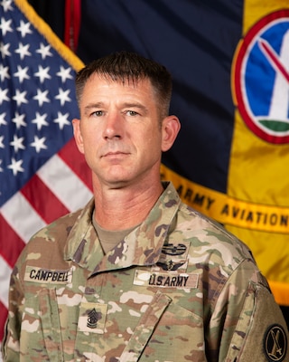Official portrait of Command Sgt. Maj. Scott Campbell in Army combat uniform with the US flag and The Army Aviation Brigade flag in the background.