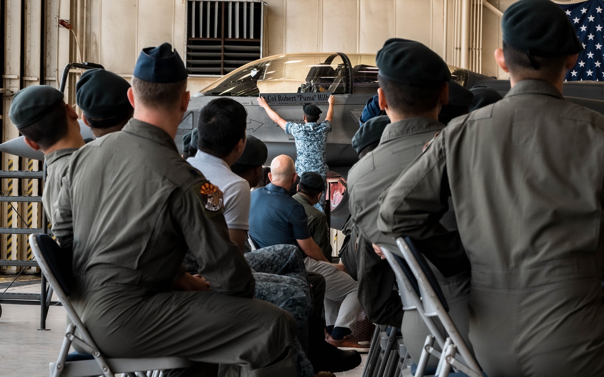 Republic of Singapore Air Force and U.S. Airmen observe the transfer of command from Lt. Col. Robert Hilby to Lt. Col. Andrew Bolint on the exterior of an F-16 Fighting Falcon during the 425th Fighter Squadron Change of Command Ceremony