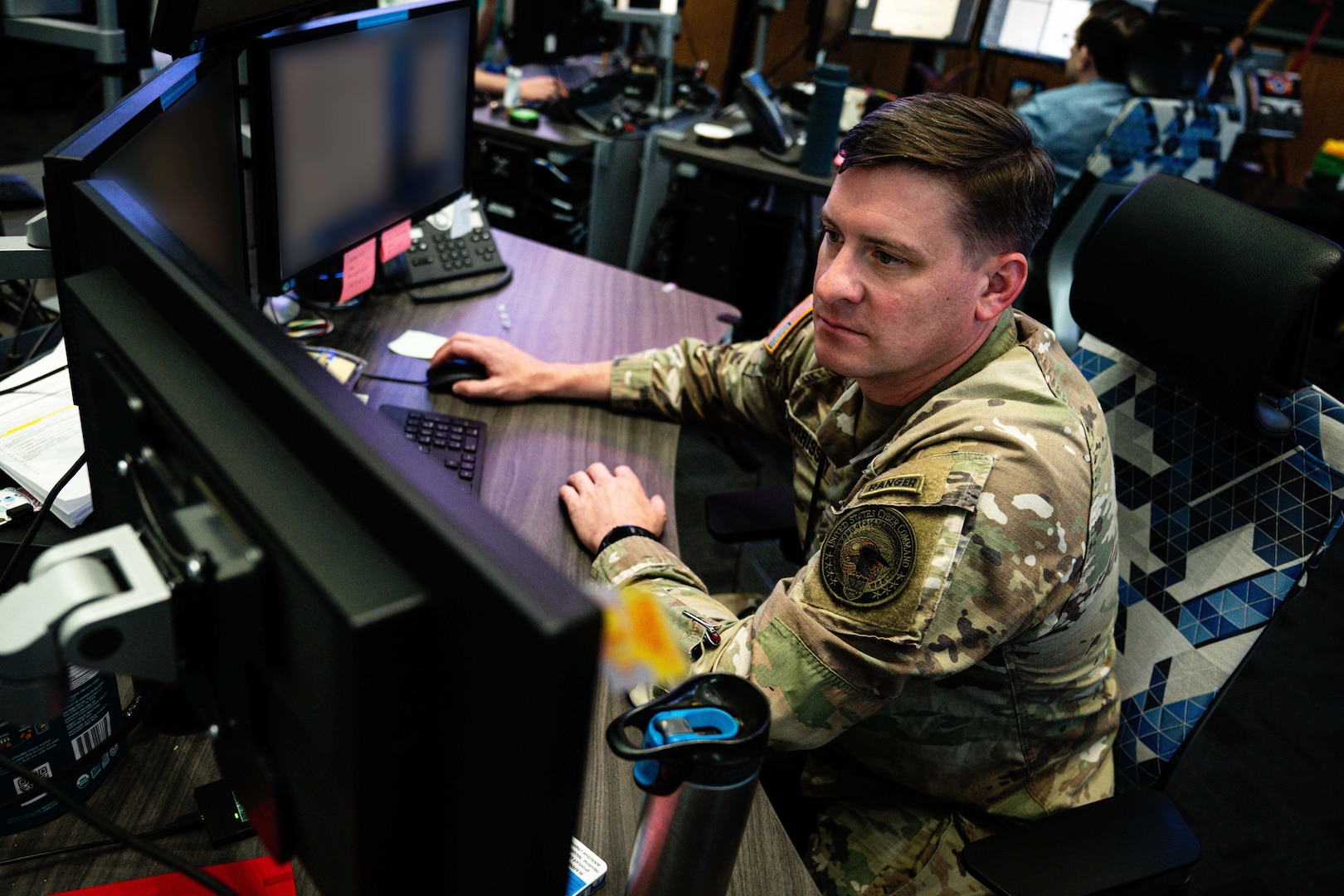 A uniformed military personnel working at a computer.