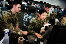 Three uniformed military personnel working at a computer