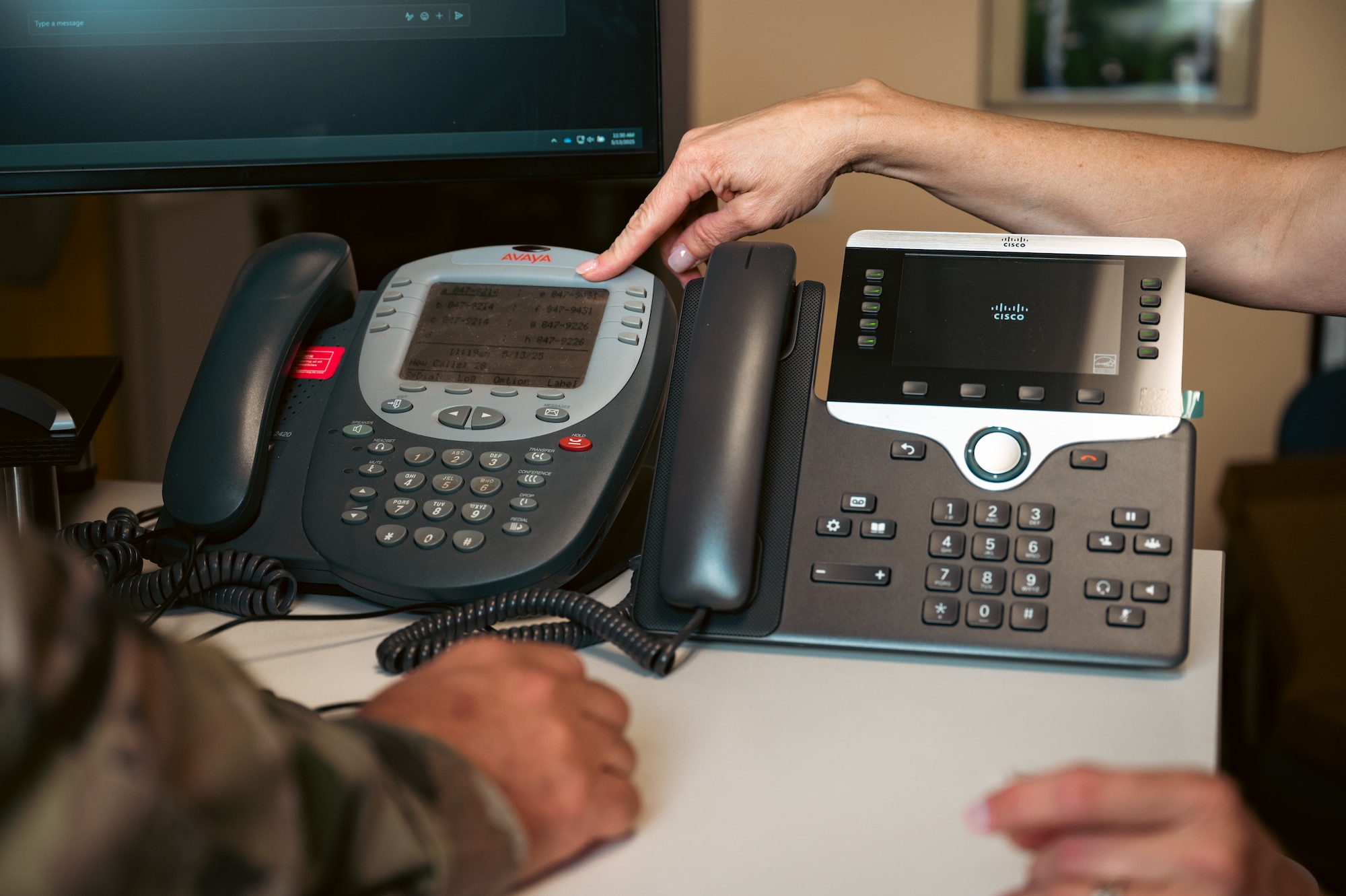 Woman points to phone on desk.