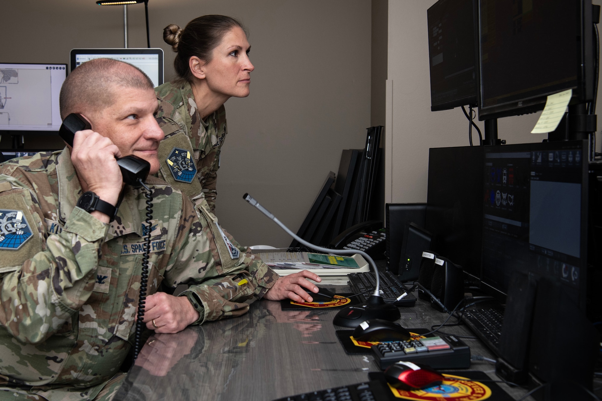 two uniformed members holding a phone and looking at a screen