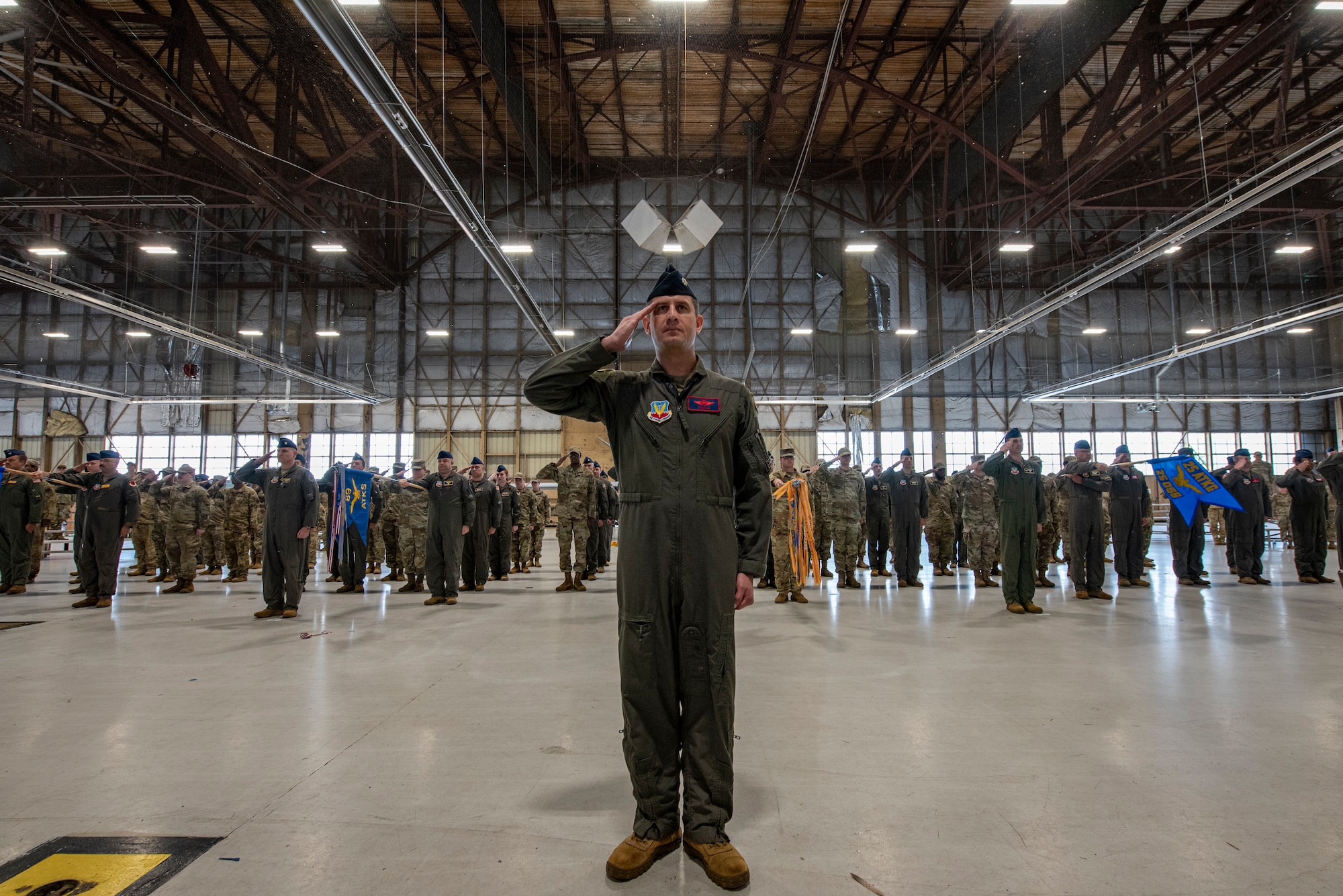 A group of military members in uniform stand at attention and salute.