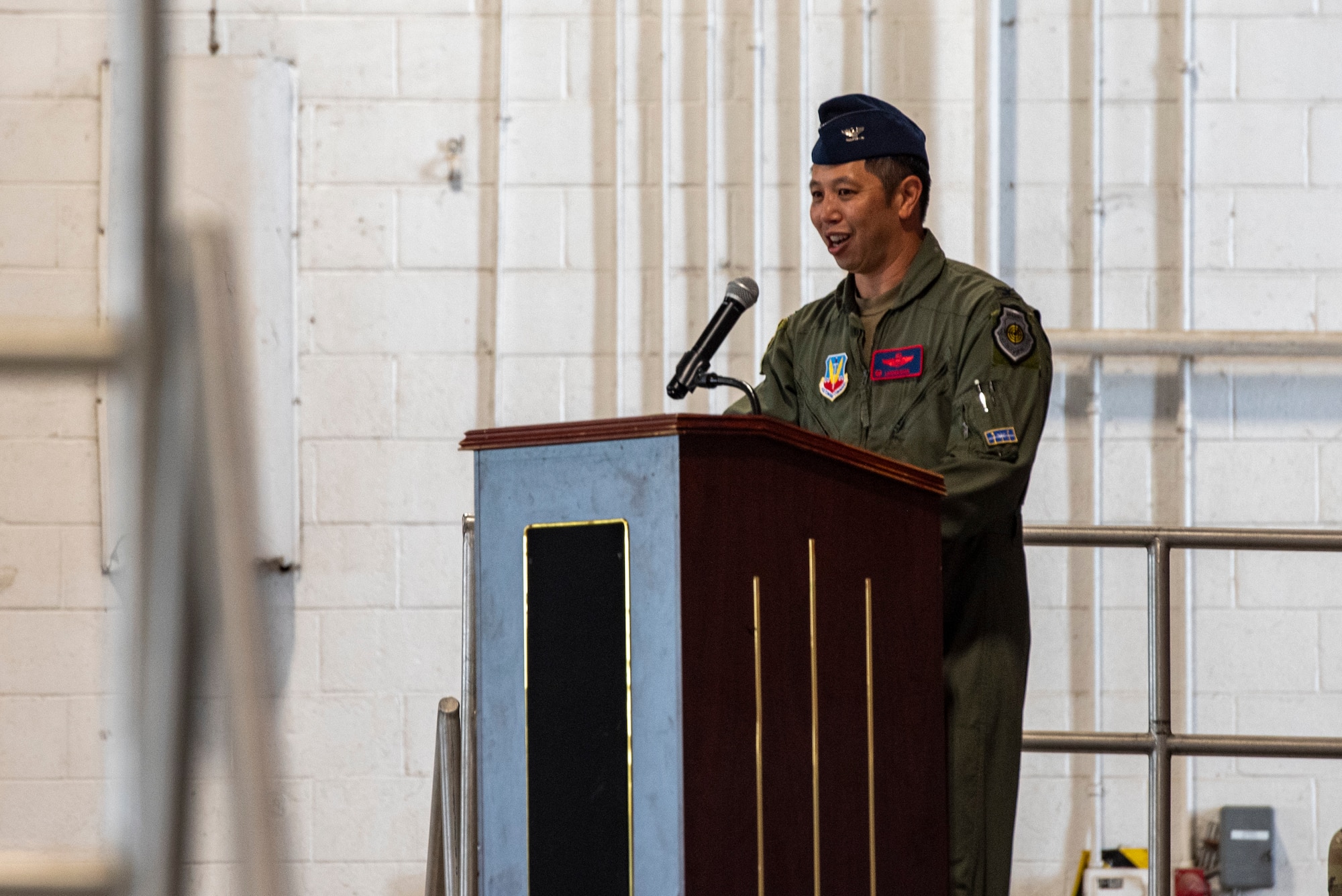 A man in a military uniform speaks into a microphone at a podium.