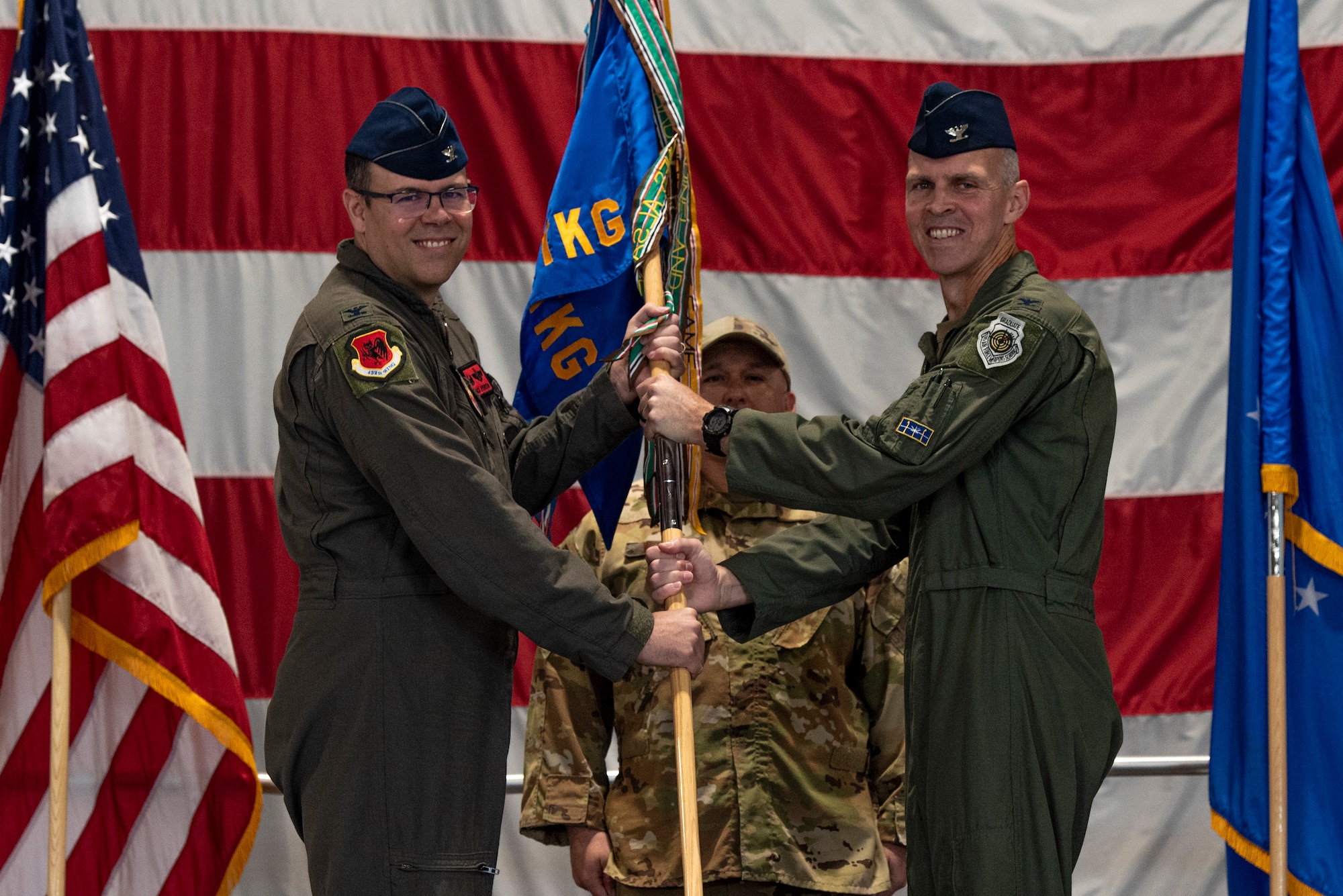 A man in a military uniform hands a guidon to another man in a military uniform.