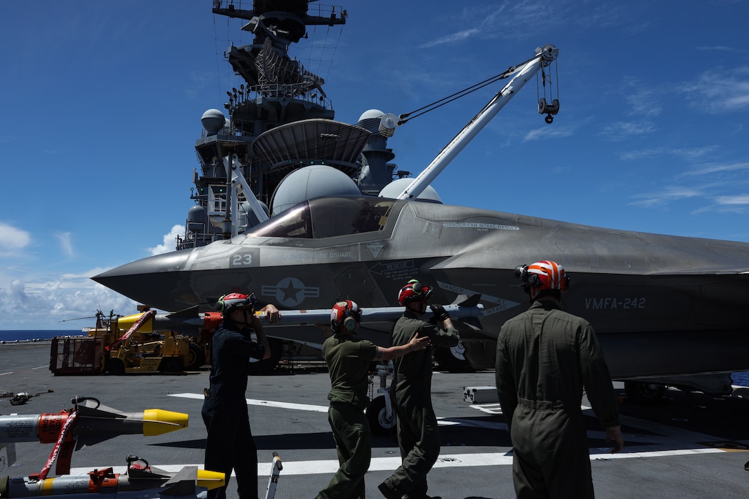 U.S. Marines load Air Intercept Missile-9X ordinance onto an F-35B Lightning II aircraft assigned to Marine Fighter Attack Squadron (VMFA) 242, 31st Marine Expeditionary Unit, during flight operations aboard the amphibious assault ship USS America (LHA 6), in the Philippine Sea, June 3, 2025. Marine F-35Bs bring a 5th generation multi-discipline strike capability to support combined-joint all domain operations in key maritime terrain. The 31st MEU is operating aboard ships of the USS America Amphibious Ready Group in the 7th Fleet area of operations, the U.S. Navy’s largest forward deployed numbered fleet, and routinely interacts and operates with allies and partners in preserving a free and open Indo-Pacific region. (U.S. Marine Corps photo by Lance Cpl. Gerardo Mendez)