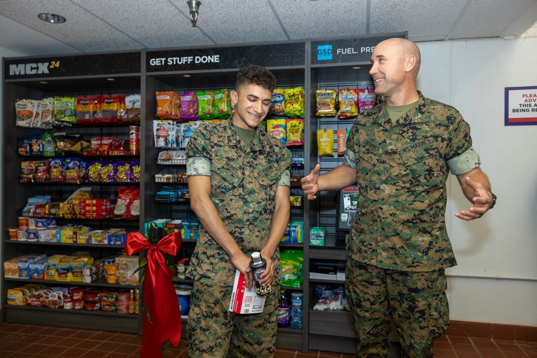 U.S. Marine Corps Lance Cpl. Daniel Grimes, administrative clerk, Headquarters and Service Battalion, U.S. Marine Corps Forces Pacific, enjoys a moment of levity with Col. Mark F. Schaefer, commanding officer, H&S Battalion, MARFORPAC during a ribbon cutting ceremony at the Single Marine Program building located on Camp H.M. Smith on May 22, 2025. The commanding officer and sergeant major of H&S Battalion, MARFORPAC along with Marine Corps Community services held a grand opening ceremony to commemorate the opening of the new Marine Corps Exchange MicroMart, which provides 24-hour meal options for those residing in the Bachelor Enlisted Quarters.