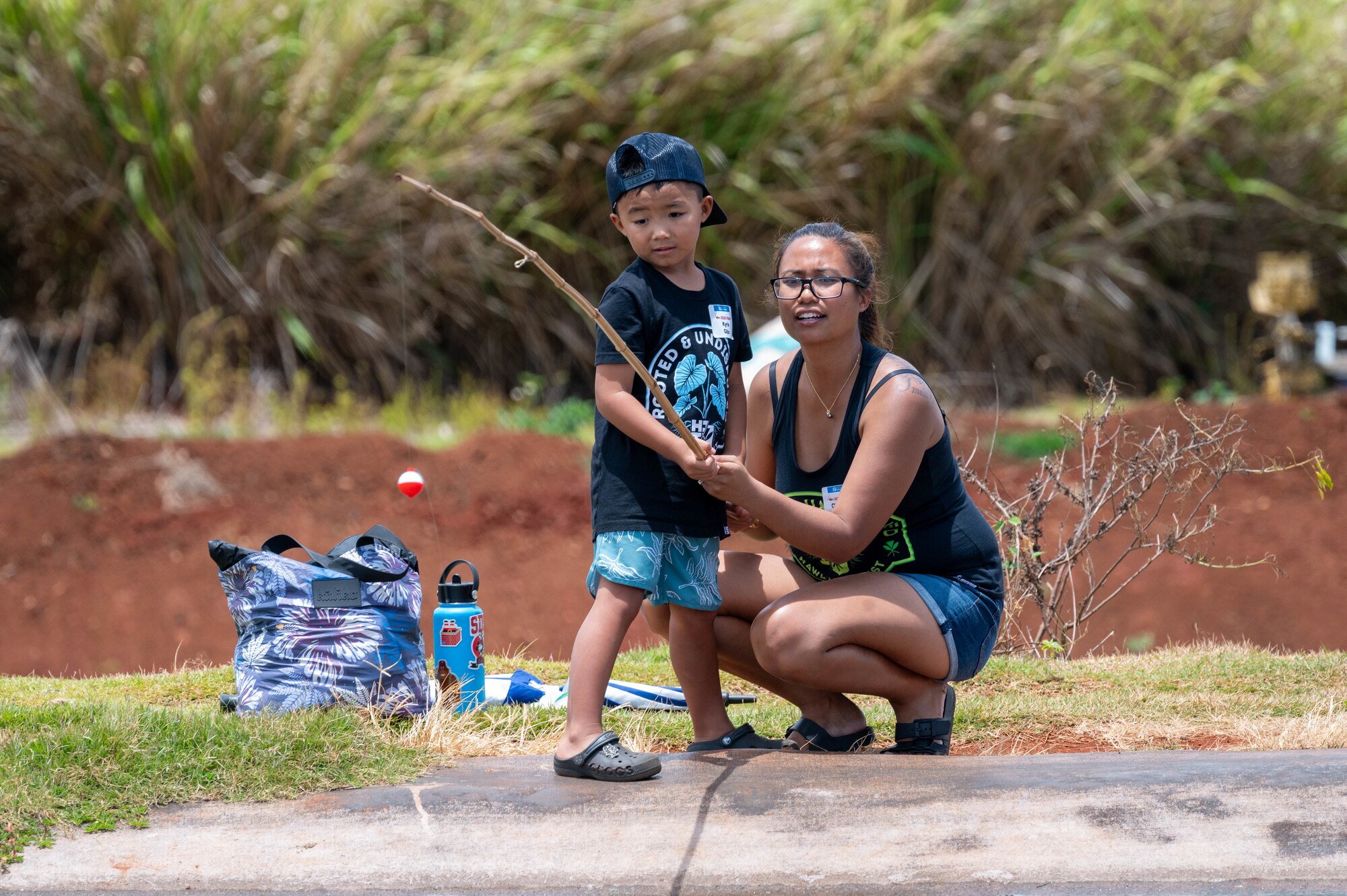 A mother assists her son while he is fishing during Keiki Fishing Day.