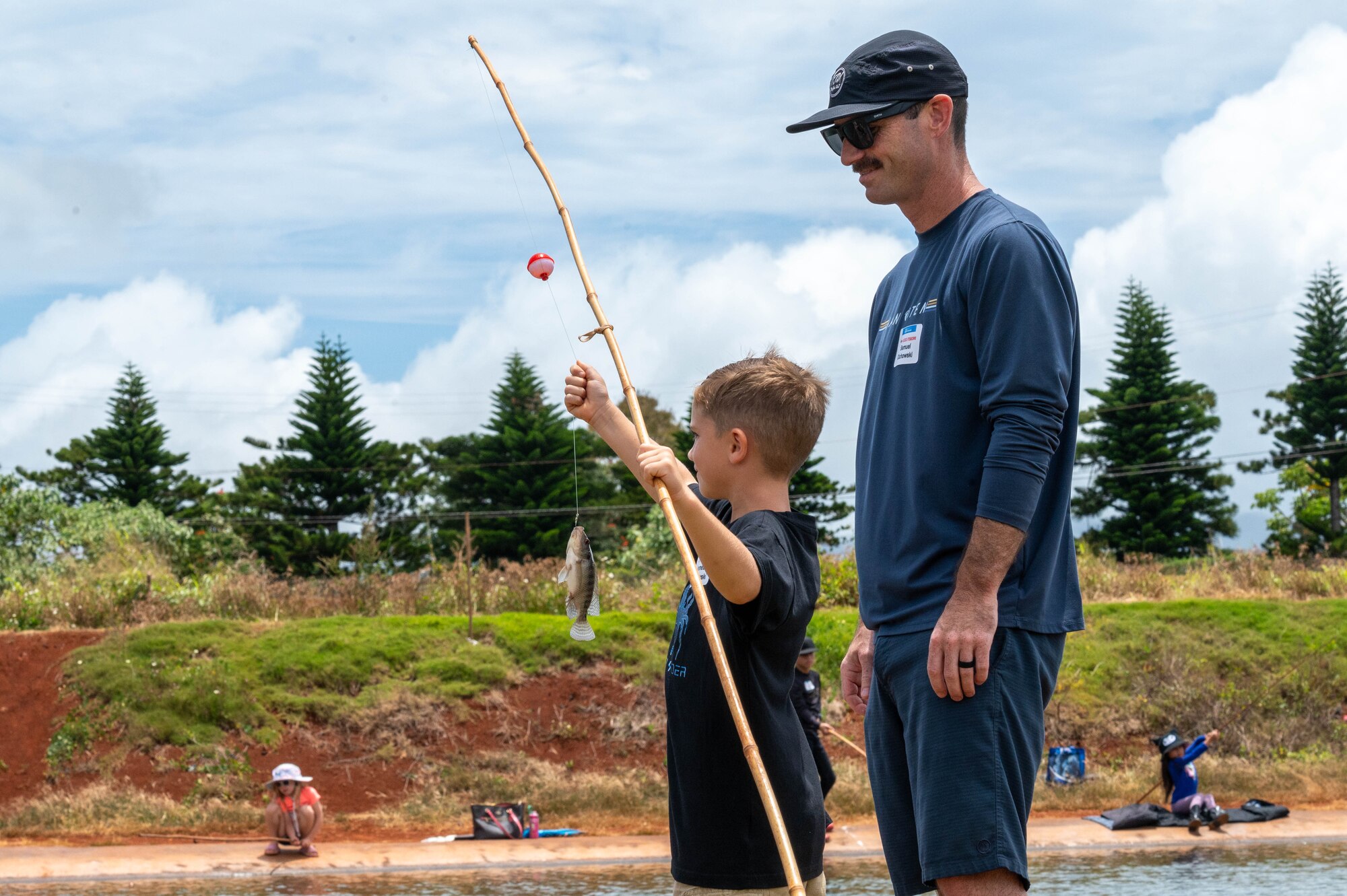 A father watches his son casts his line while fishing during Keiki Fishing Day.