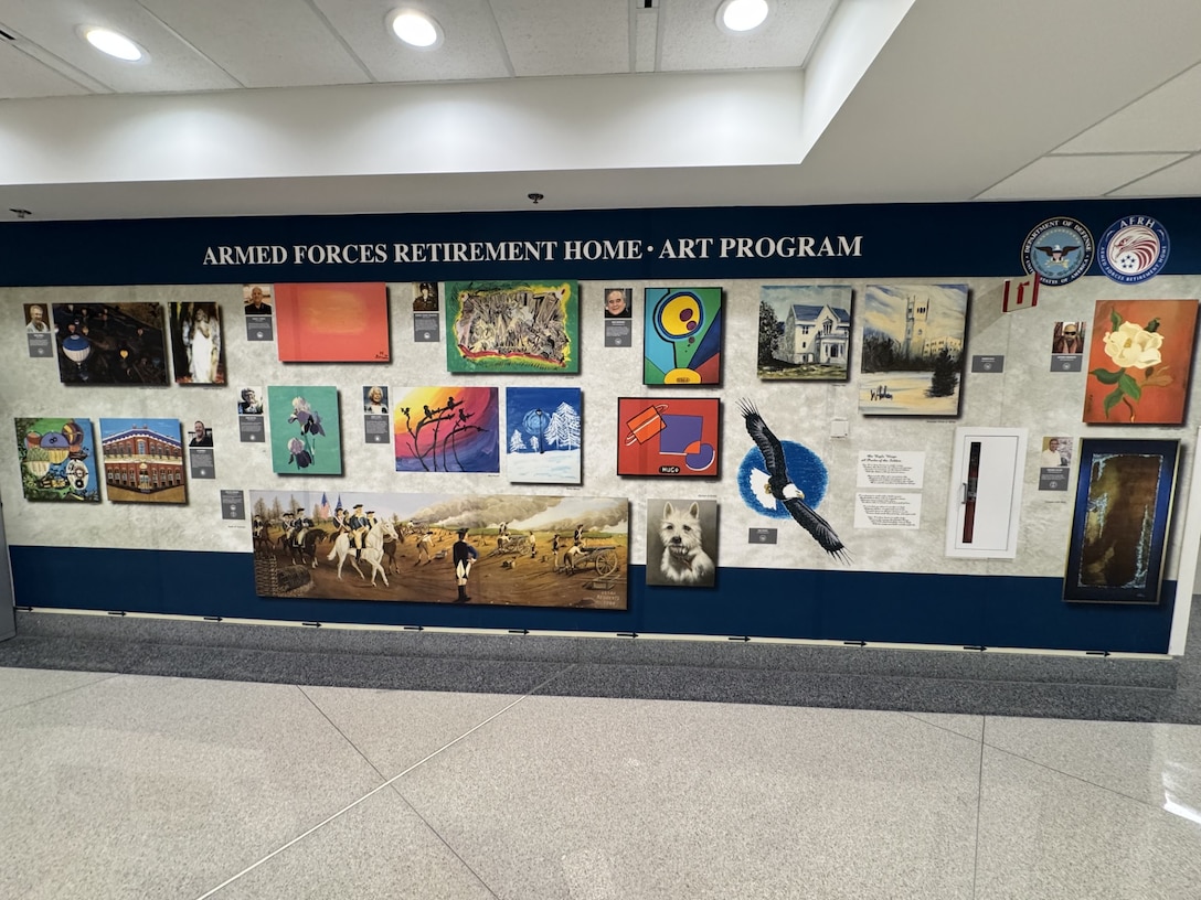 Paintings of military campaigns, buildings and nature hang on a wall.