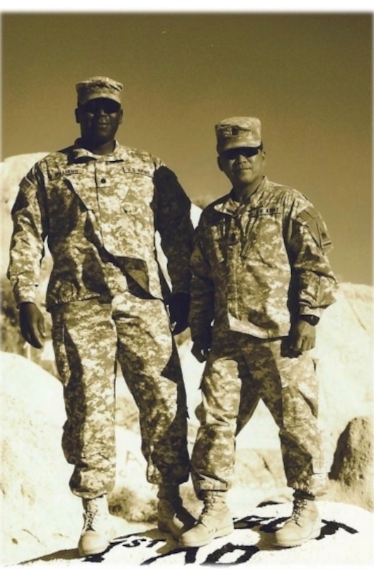 Two soldiers stand in the desert in a vintage photo.