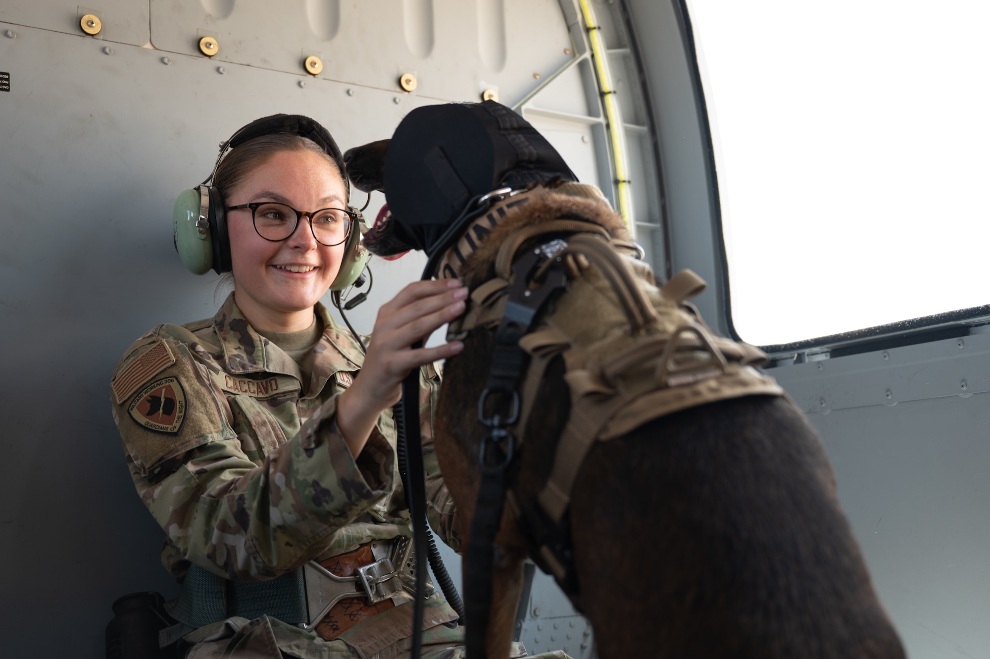 U.S. Air Force Senior Airman Julia Caccavo, 355th Security Forces Squadron military working dog handler, comforts a MWD on board an HH-60W Jolly Green II helicopter above Davis-Monthan Air Force Base, Arizona, June 3, 2025. Caccavo and her MWD participated in a familiarization training to get MWDs acclimated to flying in a helicopter. (U.S. Air Force photo by Airman Jaden Kidd)