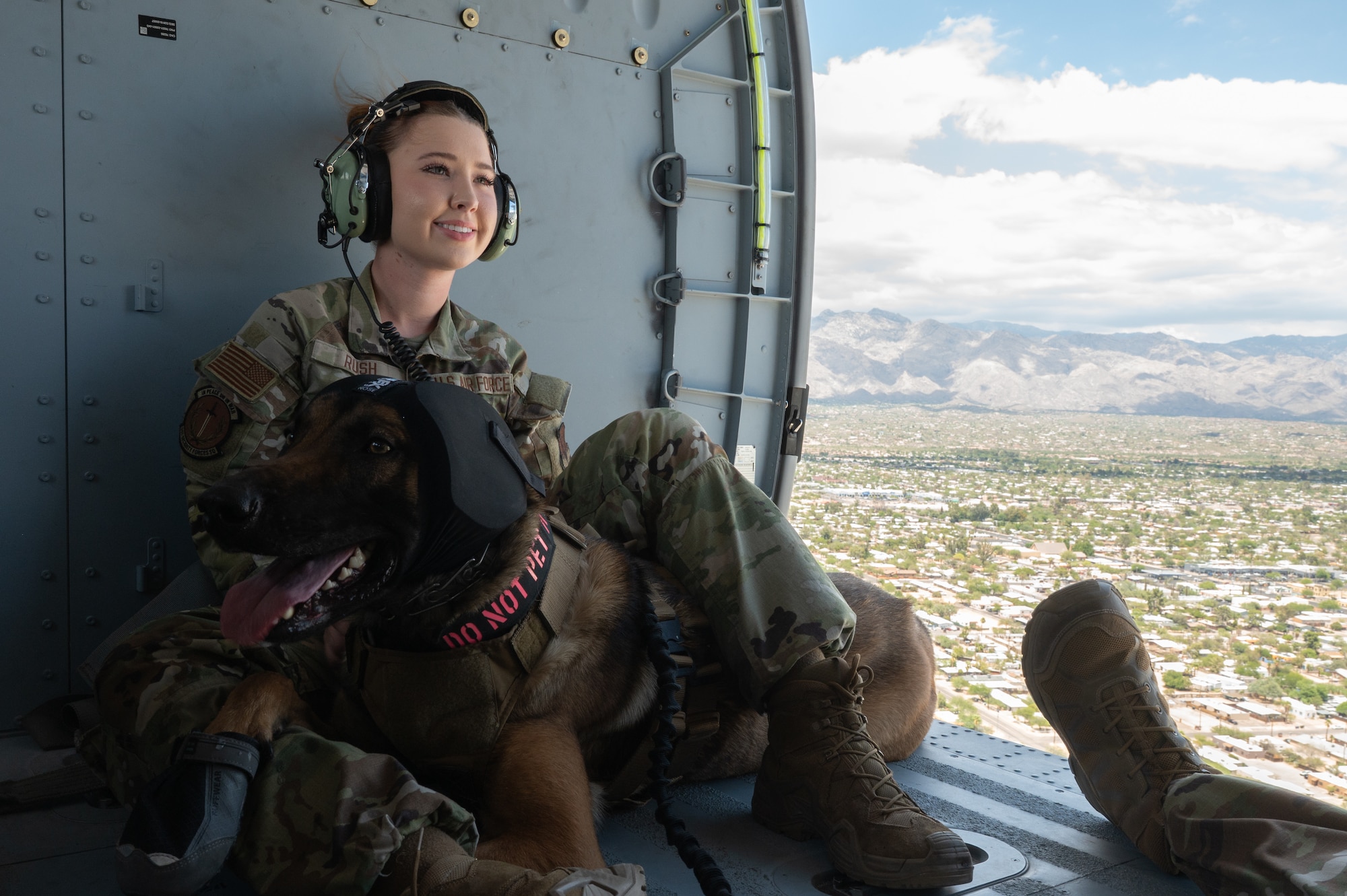 U.S. Air Force Senior Airman Kimbree Rush, 355th Security Forces Squadron military working dog handler, comforts a MWD on board an HH-60W Jolly Green II helicopter above Tucson, Arizona, June 3, 2025. Rush spent 20 minutes in the air with her MWD flying above Tucson to become comfortable on board the helicopter. (U.S. Air Force photo by Airman Jaden Kidd)