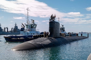 A submarine is shown next to a boat in a harbor. 