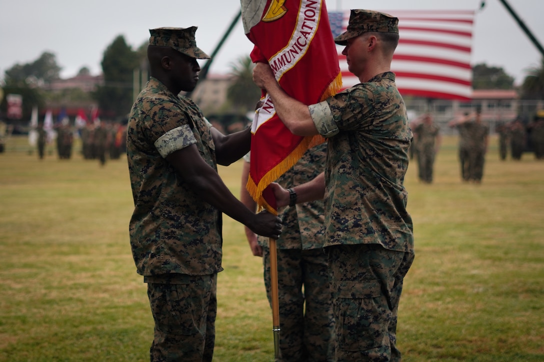 U.S. Marine Corps Lt. Col. Robert A. Doss III, right, the outgoing commanding officer for 9th Communication Battalion, I Marine Expeditionary Force Information Group, passes the organizational colors to the incoming commanding officer, Lt. Col. Raymond N. Takor, during the battalion’s change of command ceremony at Marine Corps Base Camp Pendleton, California, June 4, 2025. (U.S. Marine Corps photo by Cpl. Tyler Wilson)