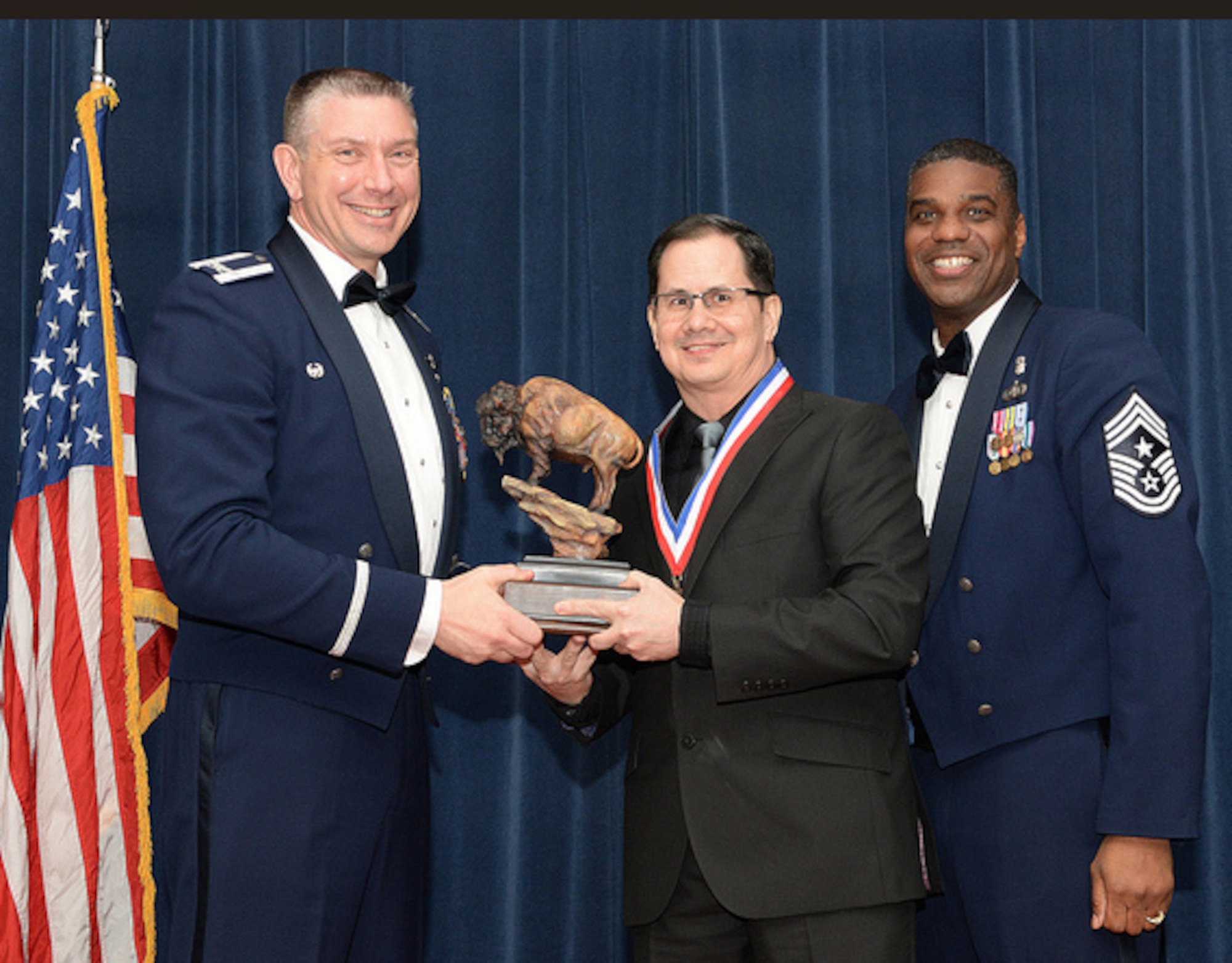 Former U.S. Air Force Col. William Spangenthal, 97th Air Mobility Wing commander, hands the Junior Civilian of the Year award to David Pelino, 97th Comptroller Squadron (CPTS) unit program coordinator, at Altus Air Force Base (AFB), Oklahoma, in 2014. Pelino began working at Altus AFB in 2010 as a dental technician before moving into administrative roles in the 97th Contracting Flight and the 97th CPTS. (Courtesy photo)
