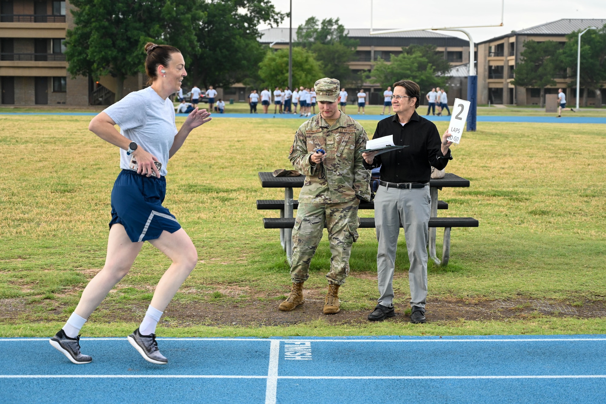 David Pelino, 97th Comptroller Squadron unit program coordinator, holds up a lap number to Tech. Sgt. Olga Vinson, 97th Air Mobility Wing judge advocate civil law non-commissioned officer, during her physical fitness test at Altus Air Force Base, Oklahoma, May 28, 2025. Pelino took over as the 97th Wing Staff Agencies physical fitness leader in 2020. (U.S. Air Force photo by Senior Airman Kari Degraffenreed)