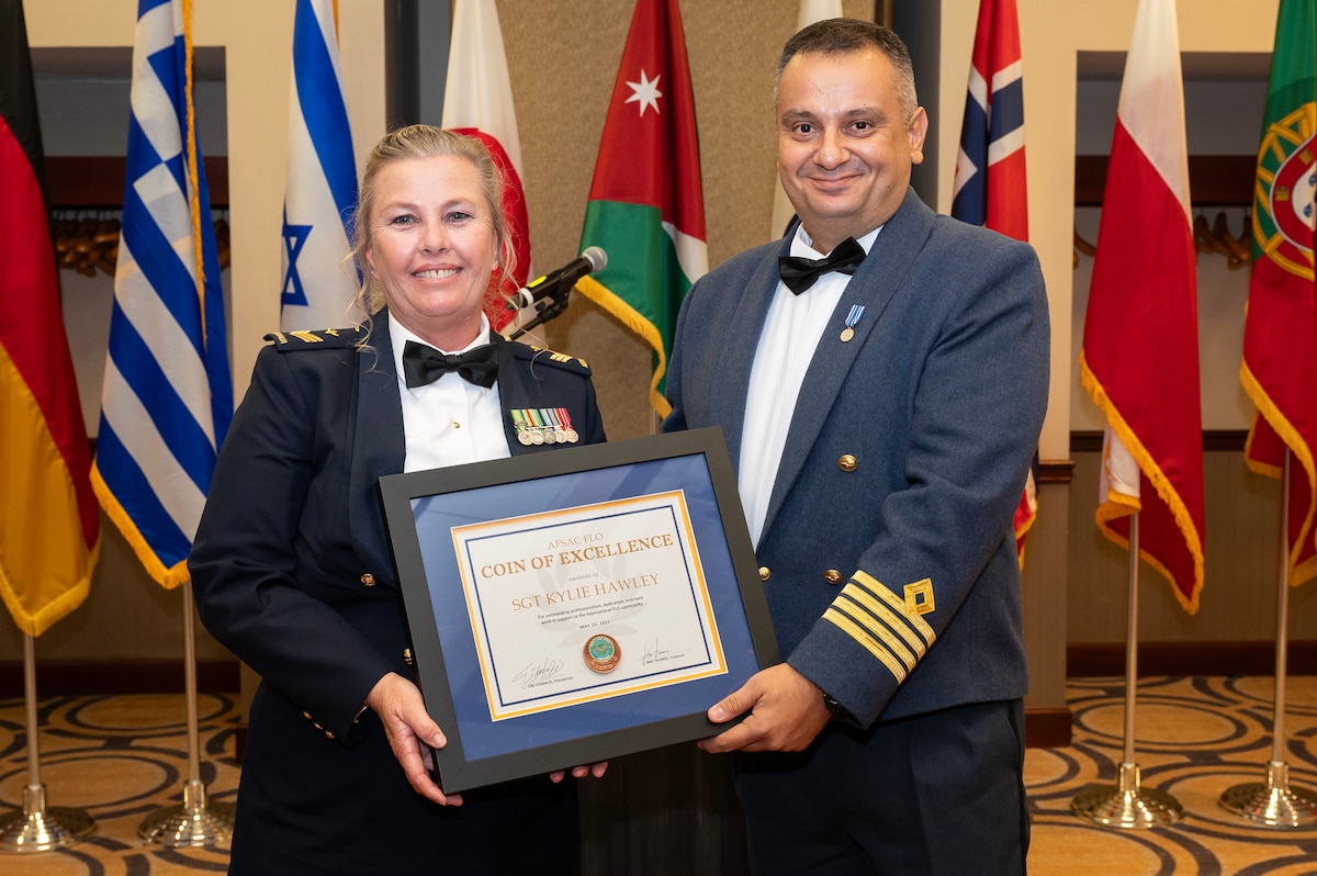 Female and male military officers hold award.