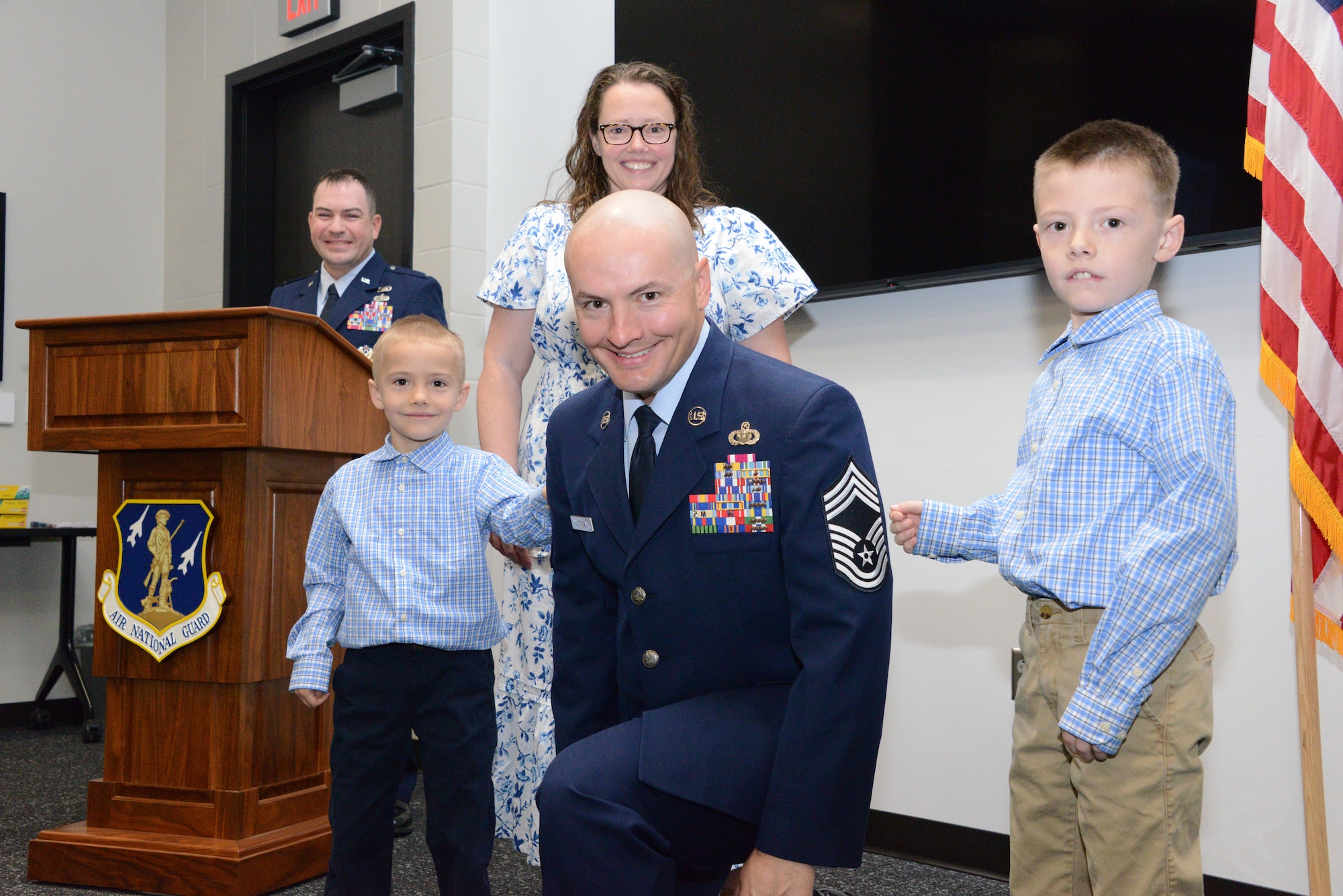 The family of U.S. Air National Guard Chief Master Sgt. Kyle Fisher, 185th Air Refueling Wing’s Finance Senior Enlisted Leader, center, assists Fisher in putting on his service coat and taking part in the tradition of “punching on” rank