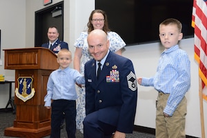 The family of U.S. Air National Guard Chief Master Sgt. Kyle Fisher, 185th Air Refueling Wing’s Finance Senior Enlisted Leader, center, assists Fisher in putting on his service coat and taking part in the tradition of “punching on” rank