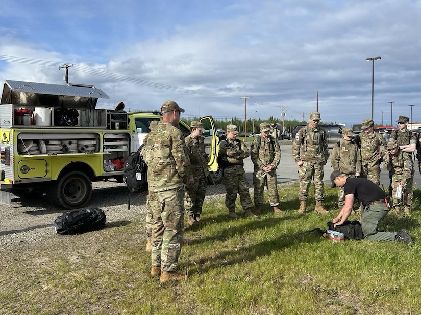 Pfc. Jack Warwick, right, an Alaska Army Guardsman with the Recruit Sustainment Program and emergency firefighter with the Alaska Division of Forestry, demonstrates field gear and speaks to cadets about the similarities between firefighting and military life on Fort Wainwright, Alaska, May 29, 2025. The training was part of the JROTC Cadet Leadership Challenge camp, designed to develop leadership skills, teamwork, and military discipline among cadets.