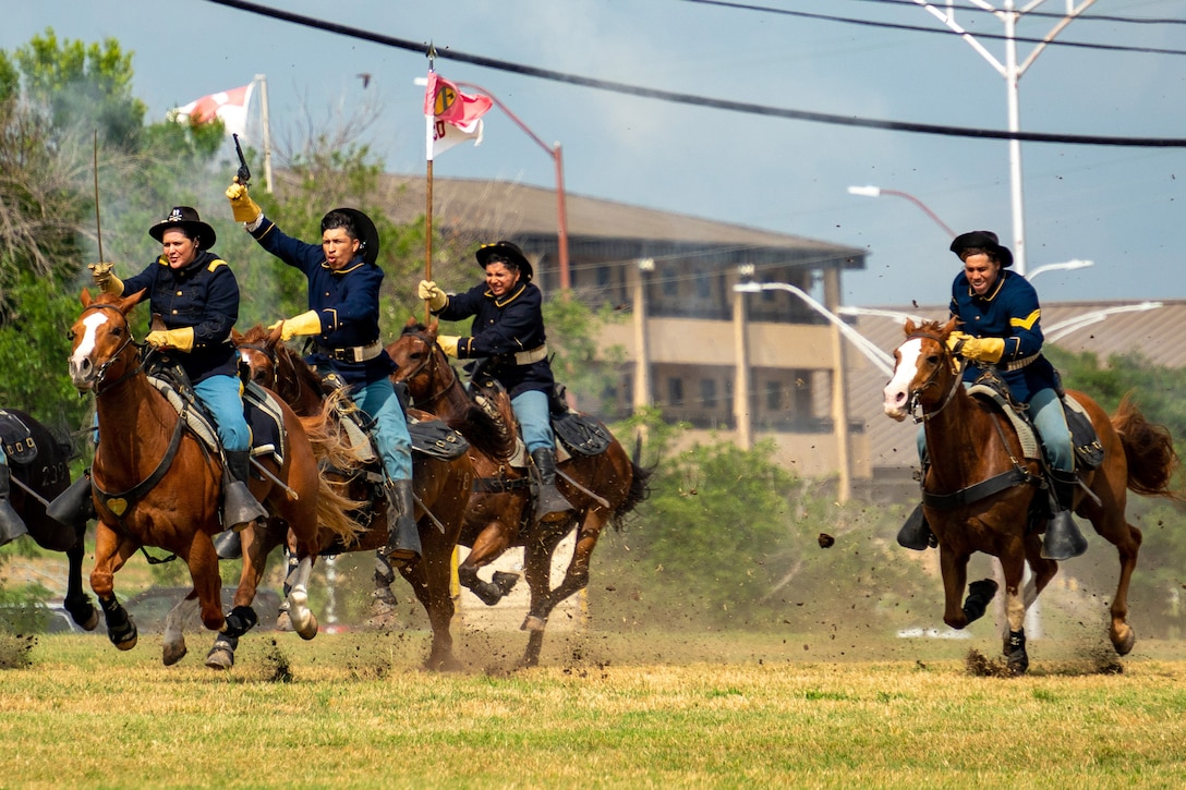 A group of soldiers in historical garb charge forward on horses.