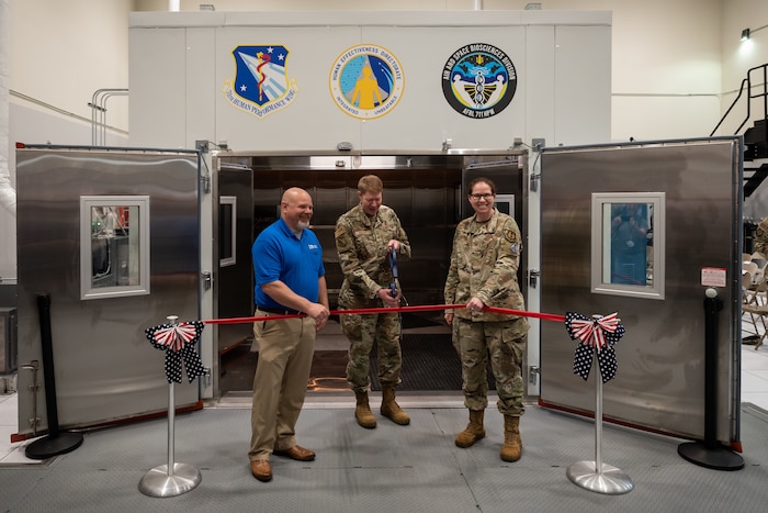 Brig. Gen. Robert K. Bogart, 711th Human Performance Wing commander, cuts a ribbon during the Research Environmental Chamber ribbon-cutting ceremony with the help of Jim Bench, left, president, Russells Technical Products, and Col. Melinda Eaton, acting director, Air Force Research Laboratory’s Human Effectiveness Directorate, at Wright-Patterson Air Force Base, Ohio, May 27, 2025. This state-of-the-art facility, part of AFRL’s Human Effectiveness Directorate, facilitates equipment and human performance evaluations by simulating environmental extremes. (U.S. Air Force photo / Richard Eldridge)