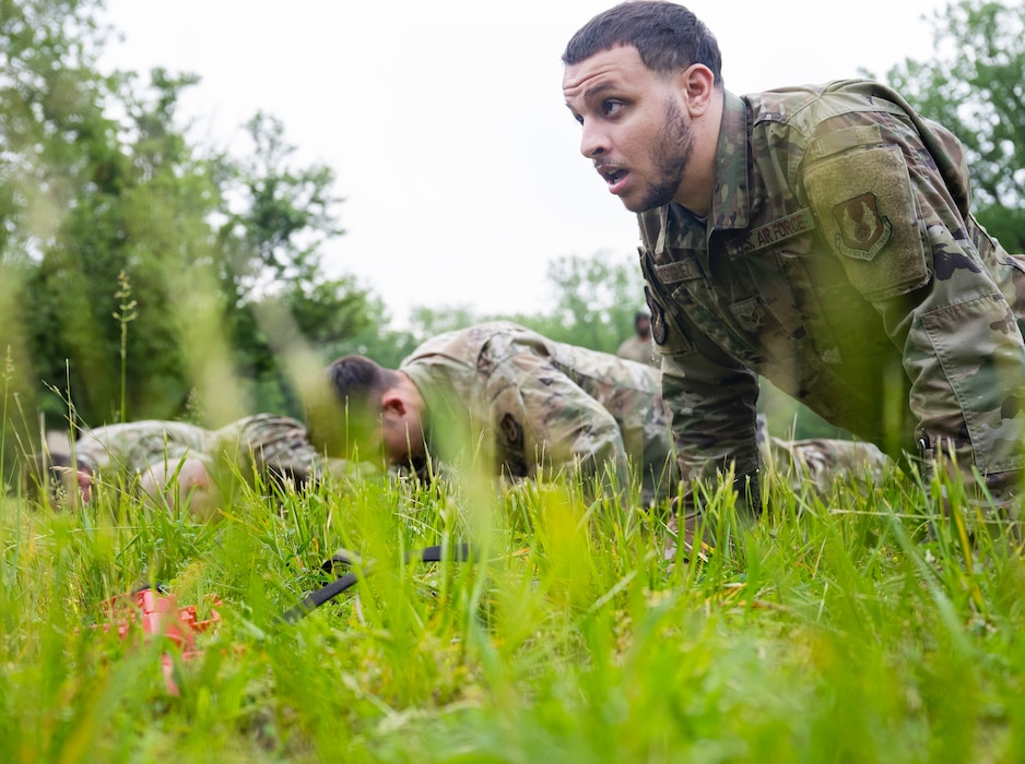An Airman is in the pushup up position in the foreground with others in the down position in the background.