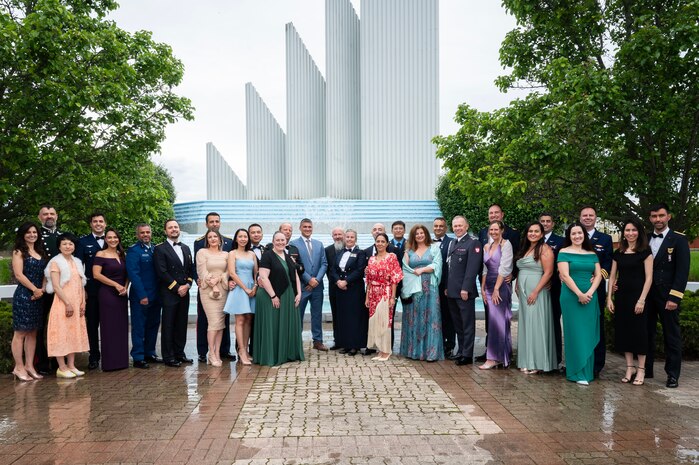 Individuals wearing formal attire pose for photo outside.