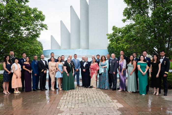 Individuals wearing formal attire pose for photo outside.