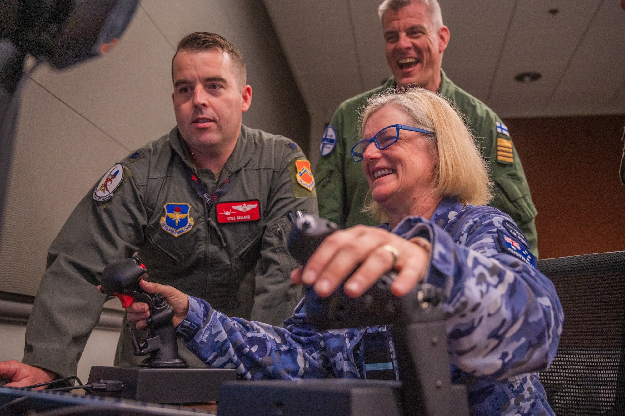 U.S. Air Force Lt. Col. Kyle Sellner, 56th Training Squadron director of operations, guides Royal Australian Air Force Air Commadore Amy Beck, RAAF air attaché, in the use of an F-35A Lightning II tabletop simulator during a base visit, June 2, 2025, at Luke Air Force Base, Arizona. While at Luke, the delegation received a wing mission brief, participated in a roundtable discussion with Brig. Gen. Berkland, toured two fighter squadrons, experienced F-35 tabletop simulators, visited an F-35 aircraft, and walked flight line. (U.S. Air Force photo by Senior Airman Elias Carrero)