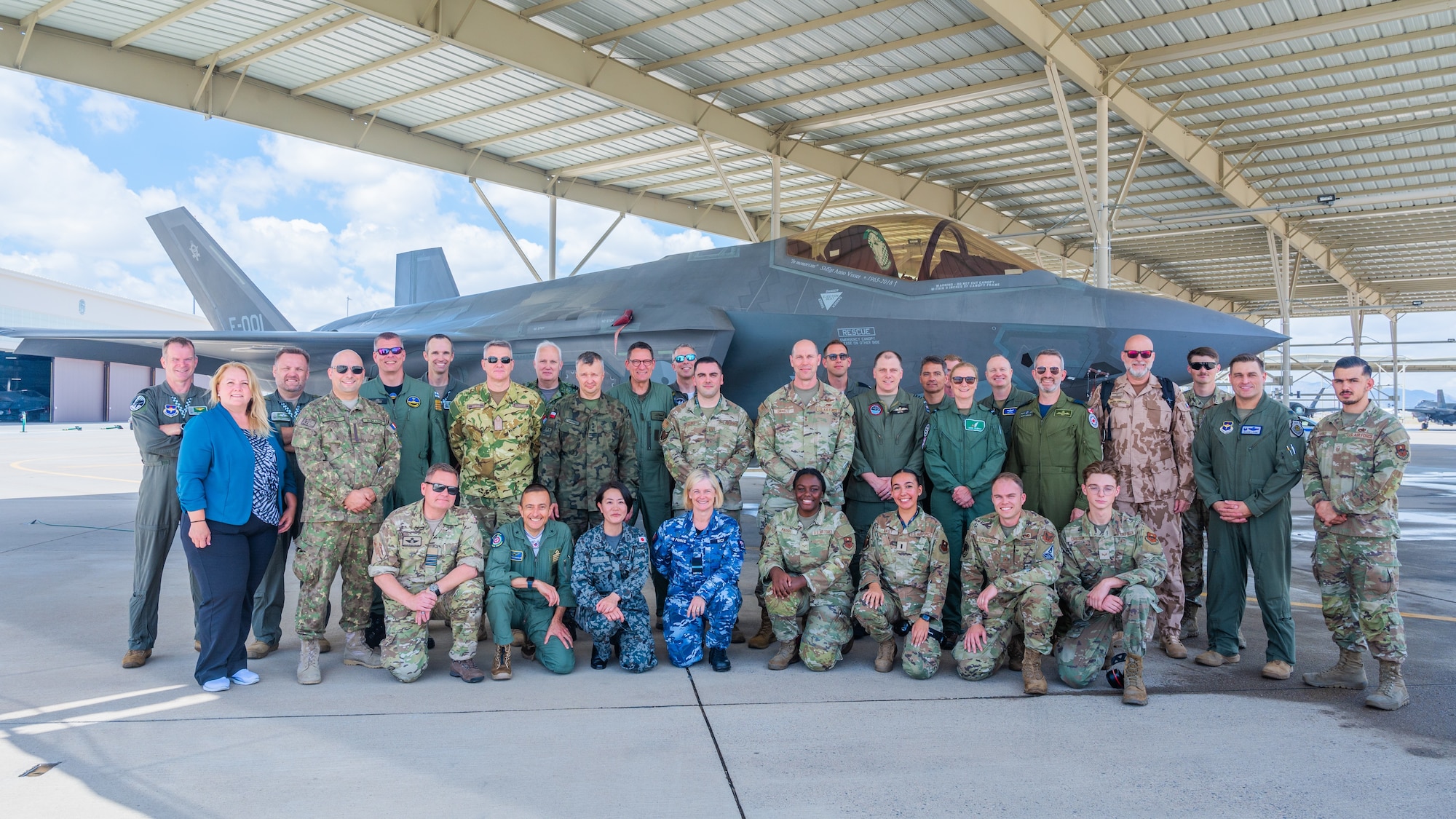 Defense attachés from 17 allied and partner nations and U.S. Air Force Airmen assigned to the 56th Fighter Wing pose for a group photo in front of an F-35A Lightning II during a base visit, June 2, 2025, at Luke Air Force Base, Arizona. The attachés visited Luke AFB to deepen cooperation on F-35 training and integration. The attachés, representing nations from Europe, the Middle East, Asia, and Oceania, received an in-depth look at how the United States and its partners are advancing fifth-generation fighter integration. (U.S. Air Force photo by Senior Airman Elias Carrero)
