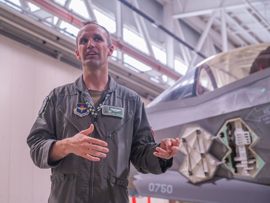 U.S. Air Force Lt. Col. Shayne Carroll, 308th Fighter Squadron commander, speaks to defense attachés from allied and partner nations about the capabilities of the F-35A Lightning II during a base visit, June 2, 2025, at Luke Air Force Base, Arizona. While at Luke, the delegation received a wing mission brief, participated in a roundtable discussion with Brig. Gen. Berkland, toured two fighter squadrons, experienced F-35 tabletop simulators, visited an F-35 aircraft, and walked the flight line. (U.S. Air Force photo by Senior Airman Elias Carrero)