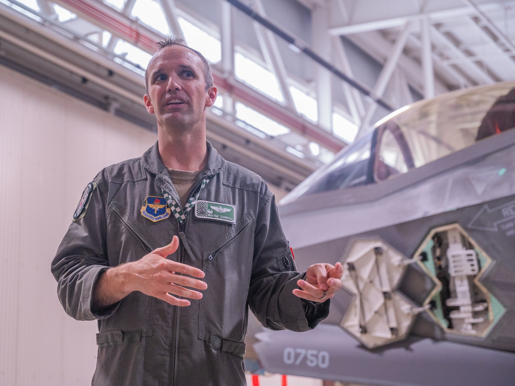 U.S. Air Force Lt. Col. Shayne Carroll, 308th Fighter Squadron commander, speaks to defense attachés from allied and partner nations about the capabilities of the F-35A Lightning II during a base visit, June 2, 2025, at Luke Air Force Base, Arizona. While at Luke, the delegation received a wing mission brief, participated in a roundtable discussion with Brig. Gen. Berkland, toured two fighter squadrons, experienced F-35 tabletop simulators, visited an F-35 aircraft, and walked the flight line. (U.S. Air Force photo by Senior Airman Elias Carrero)