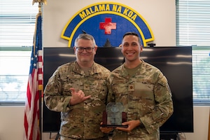 U.S. Air Force Maj. Timothy Cummings, member of the 624th Aeromedical Staging Squadron poses for a photo holding an award at Joint Base Pearl Harbor-Hickam, Hawaii, April 6, 2025.
