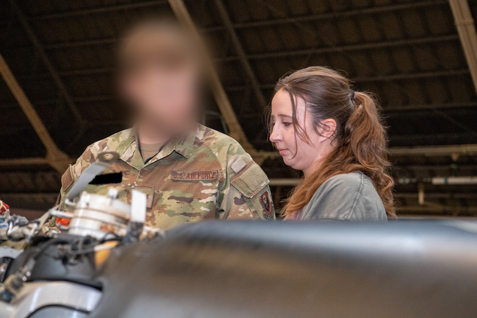 An Airman assigned to the 353rd Special Operations Wing shows CV-22 Osprey components to a military spouse.