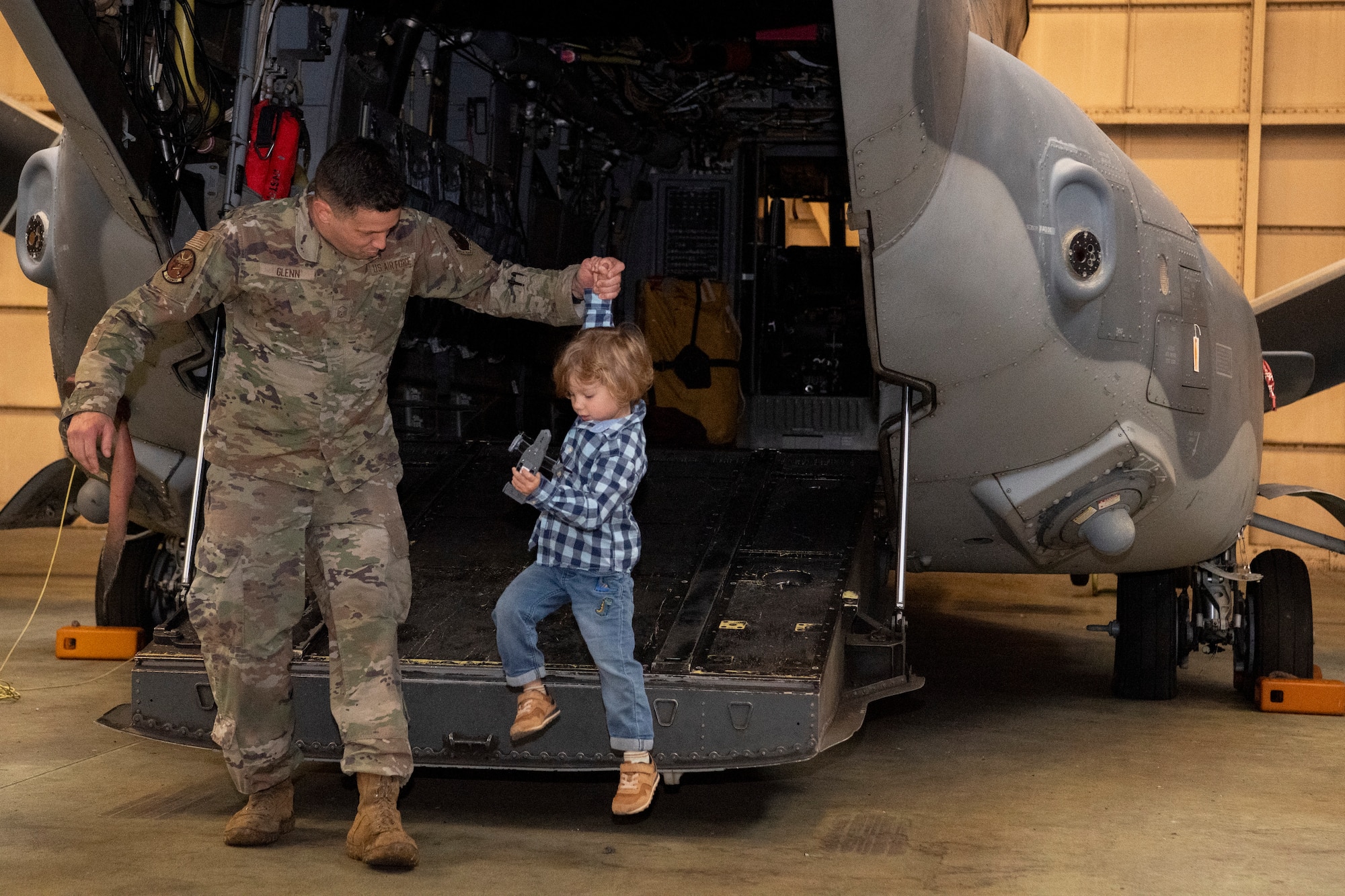 An Airman assigned to the 353rd Special Operations Wing helps a family member off of a CV-22 Osprey.