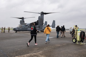Military spouses prepare to board a CV-22 Osprey.
