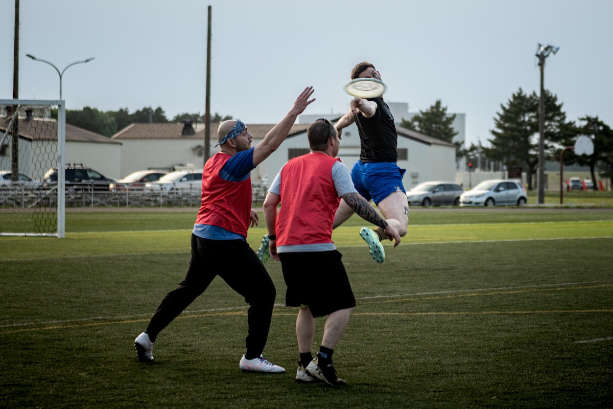 A participant of Sakura Olympics 2025 throws a frisbee over his back in a game of ultimate frisbee.