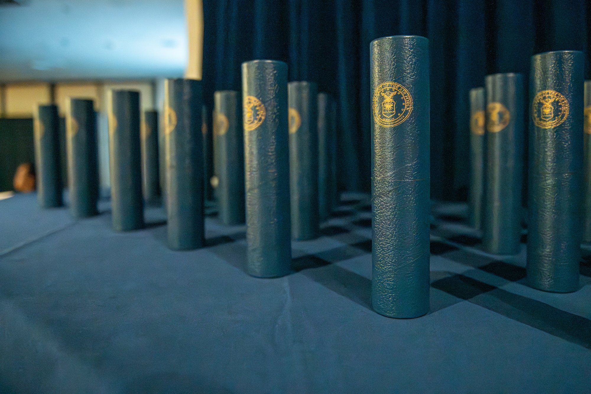 Blue diplomas sit upright on a table draped in blue cloth.