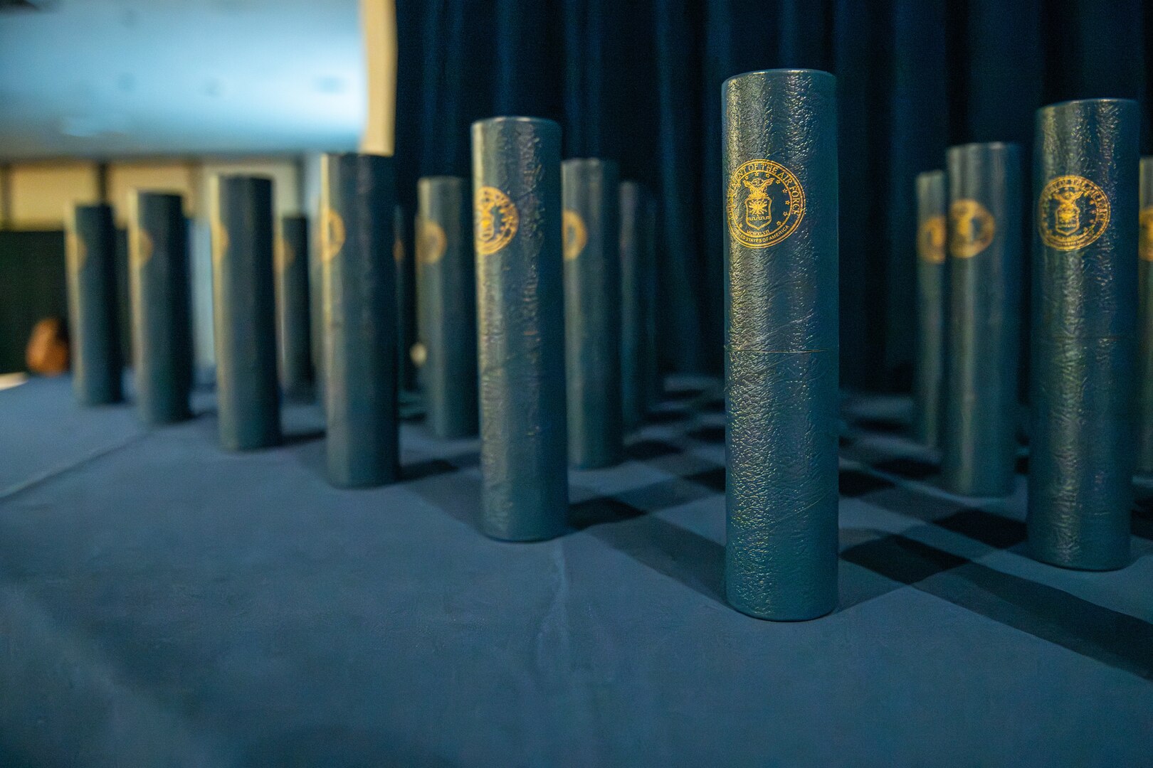 Blue diplomas sit upright on a table draped in blue cloth.
