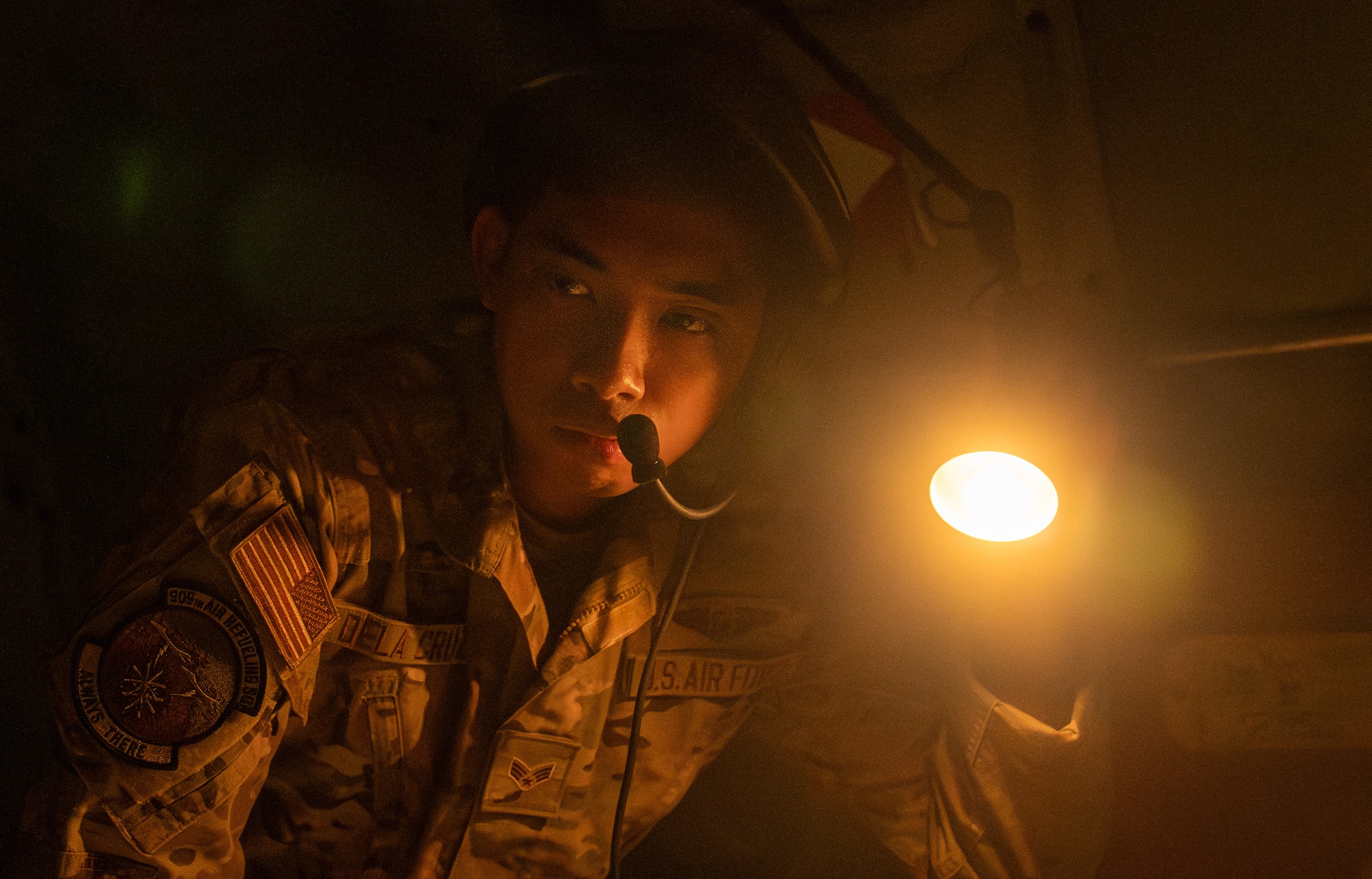 a U.S. Air Force servicemember shines a light will checking an aircraft.