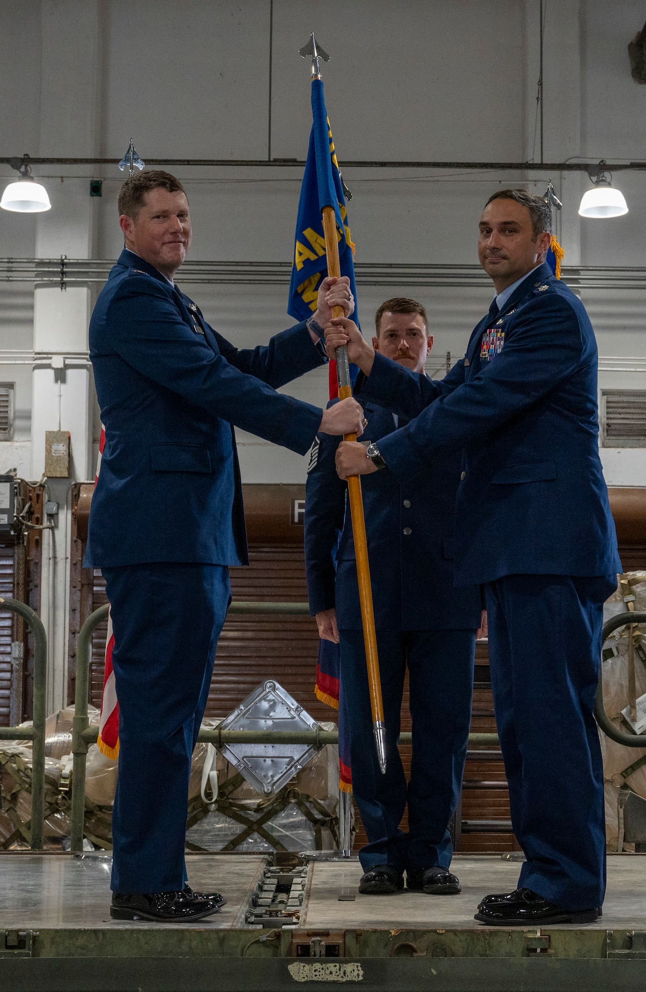 Col. Troy Pierce, commander of the 715th Air Mobility Operations Group, hands the guidon to Lt. Col. Geoffrey Britzke, incoming commander of the 734th Air Mobility Squadron, during a change of command ceremony at Andersen Air Force Base, Guam, June 4, 2025.