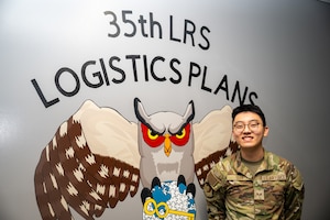 Wild Weasel of the Week (WWoW), U.S. Air Force Senior Airman Davis Qian, 35th Logistics Readiness Squadron (LRS) base support agreement manager, poses in front of a mural at his work center at Misawa Air Base, Japan, June 5, 2025.