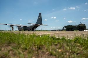 A wide view of an aircraft and military vehicle on a flightline